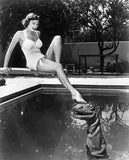 Marie Windsor sits a diving board a swimming pool touching toe to - Old Photo Model