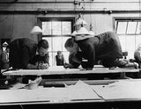 Designers kneeling on a drawing board as they work in an office Old Photo Model