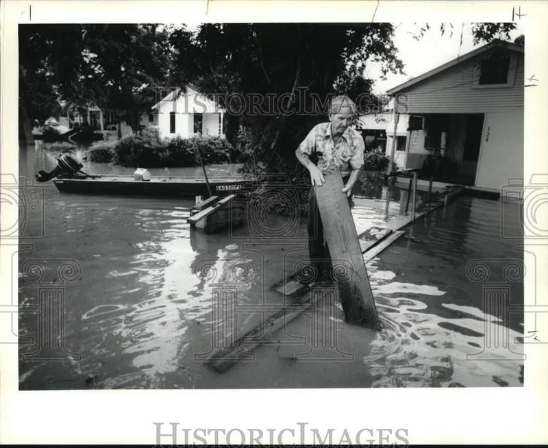 1990 Press Photo Flood - Wilfred Dauzat lays board as walkway in his front yard Model