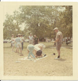 vintage color photo people men women back to camera playing twister game on lawn Model